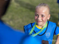 Girl in soccer uniform receiving medal from coach