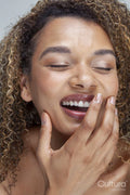 Close-up of smiling woman with curly hair and eyes closed