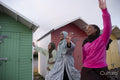 Cheerful Muslim friends waving while walking next to beach huts