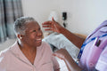 Caregiver assisting smiling senior woman with hearing aid