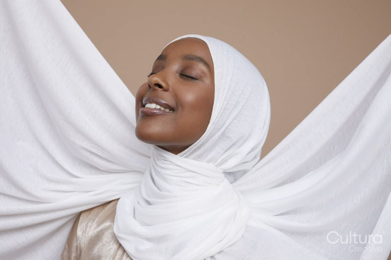 Studio shot of smiling young woman in white hijab
