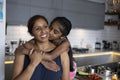 Girl embracing and kissing mother in kitchen