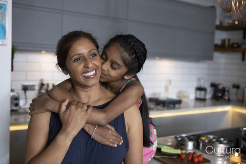 Girl embracing and kissing mother in kitchen