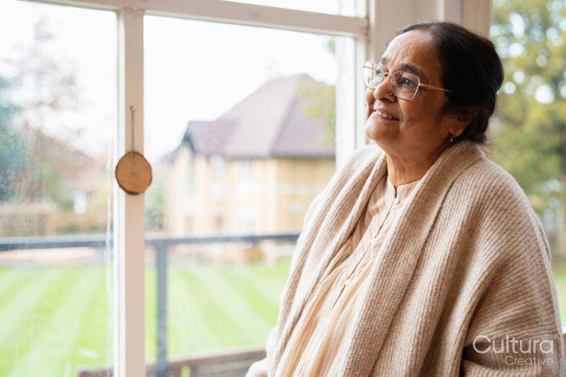 Senior woman wearing eyeglasses looking through window in nursing home