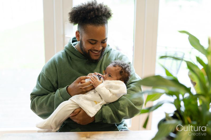 Father feeding baby daughter at home