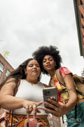 Two women using phone in street, low angle view