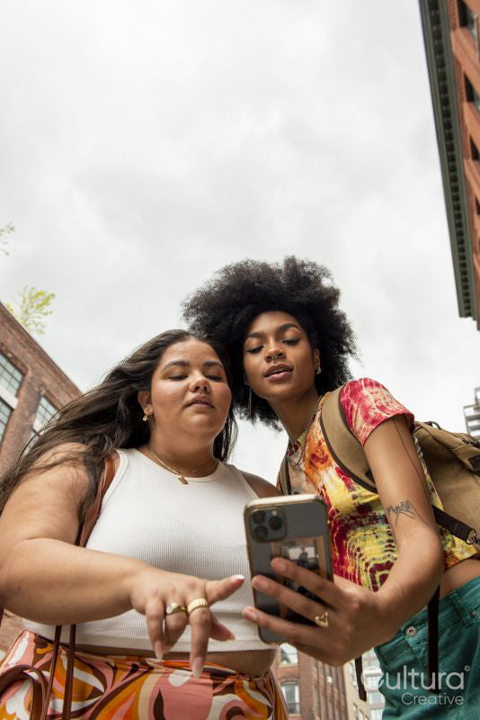 Two women using phone in street, low angle view