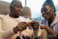 Smiling nurse looking at senior woman knitting in nursing home