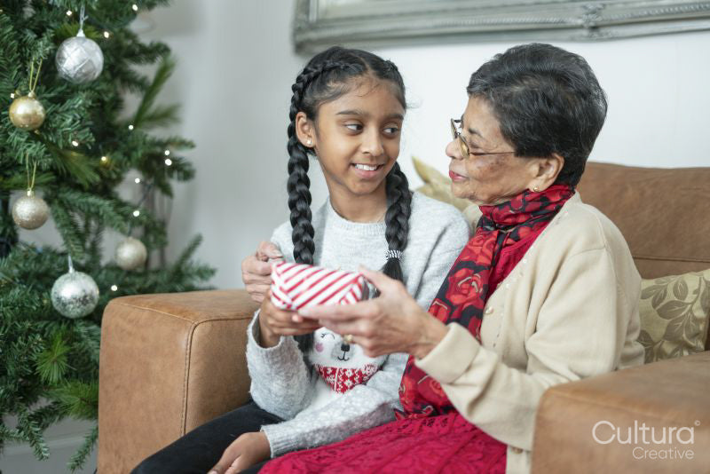 Smiling girl with grandmother holding Christmas gift