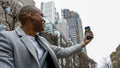 Business man using phone to take selfie in city