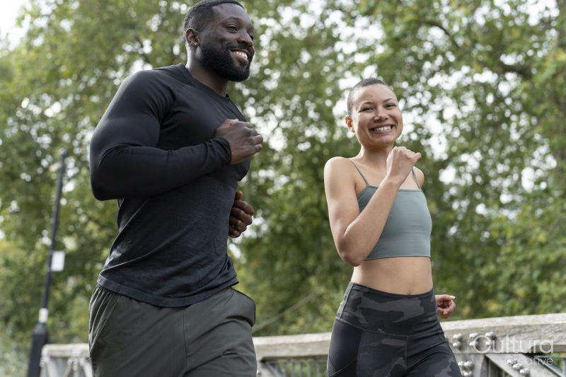 Smiling athletic couple jogging on footbridge in park