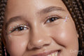 Close-up of smiling girl with decorative stickers on face