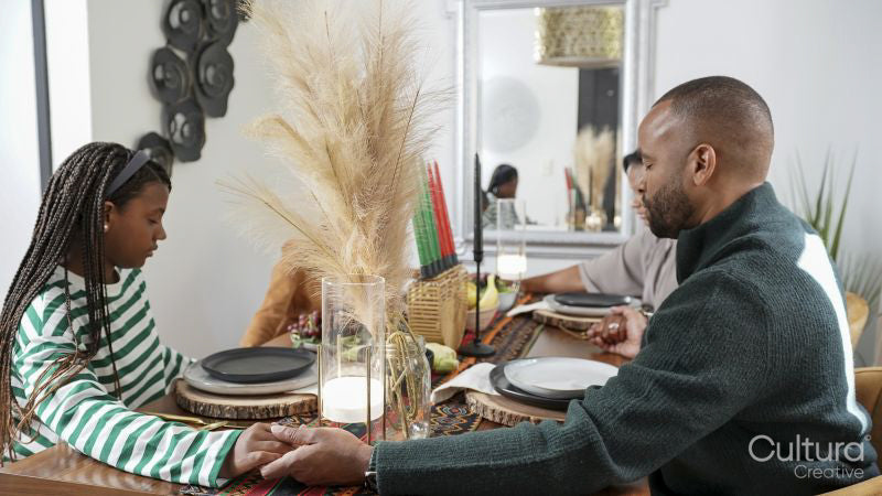 Family with children praying before Kwanzaa meal