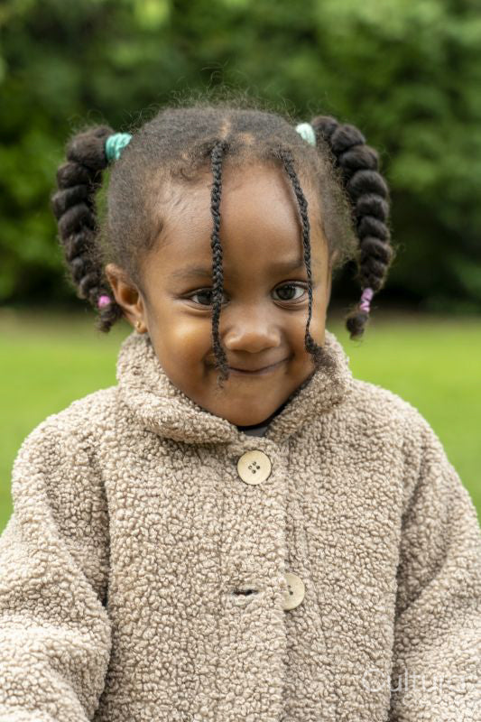 Portrait of smiling girl in coat standing in park in autumn