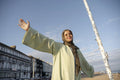 Portrait of smiling Muslim woman standing with arms outstretched on sunny day