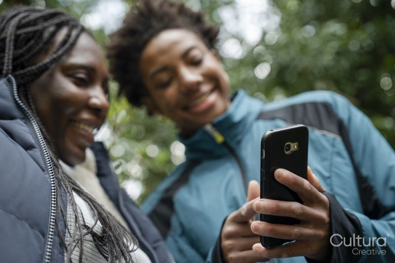 Mother and daughter looking at smart phone in park during walk