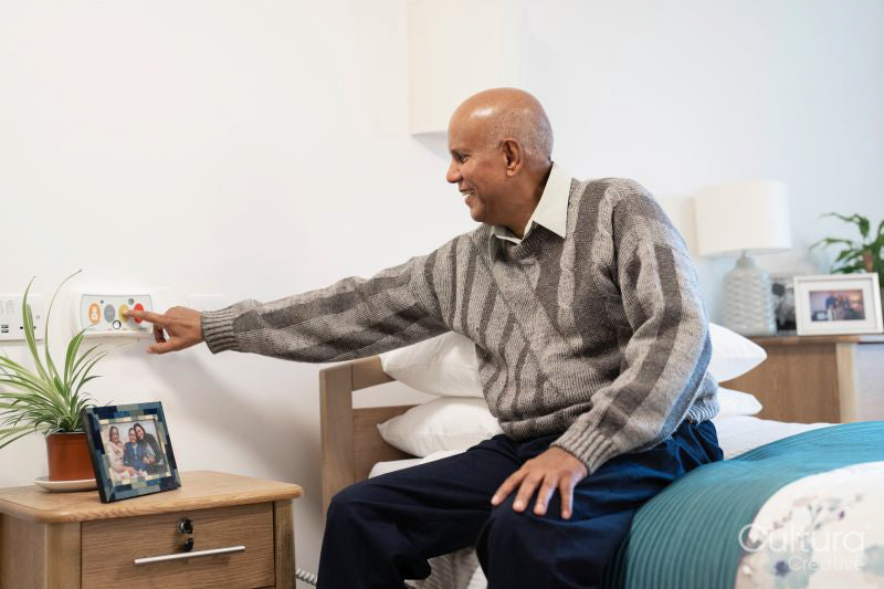 Senior man pushing call button in his room at nursing home