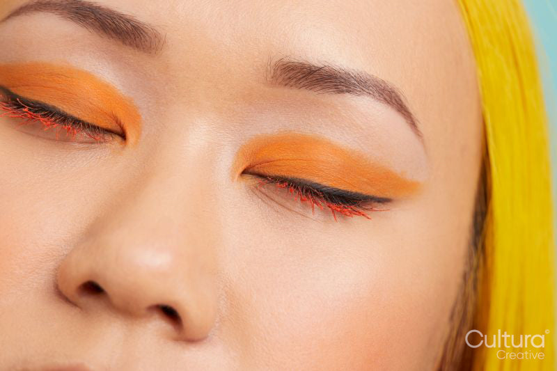 Young woman with orange make up, eyes closed