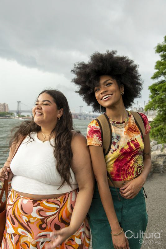Two young women posing by river