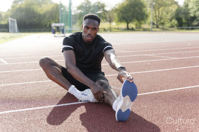 Athlete stretching legs before training at sports track