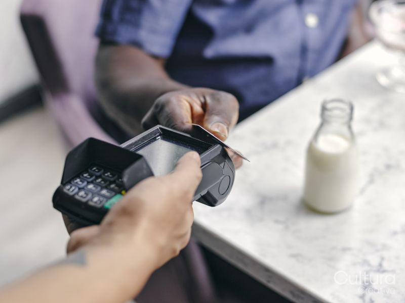 Close-up of man paying with smart phone at cafe table