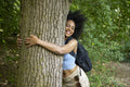 Young woman hiking in forest, hugging tree
