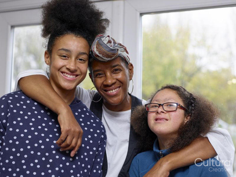 Portrait of mother embracing two daughters at home