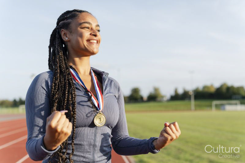 Portrait of female athlete celebrating with medal