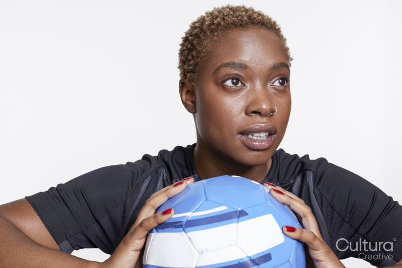 Studio portrait of female soccer player with ball