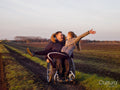 Happy woman and man on wheelchair in field