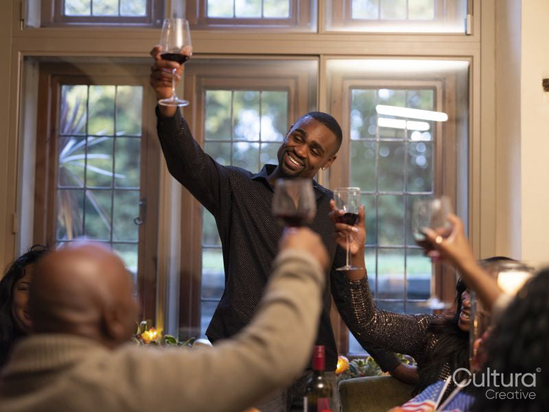 Family raising toast with red wine at Thanksgiving dinner