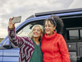 Female couple taking selfie in front of van