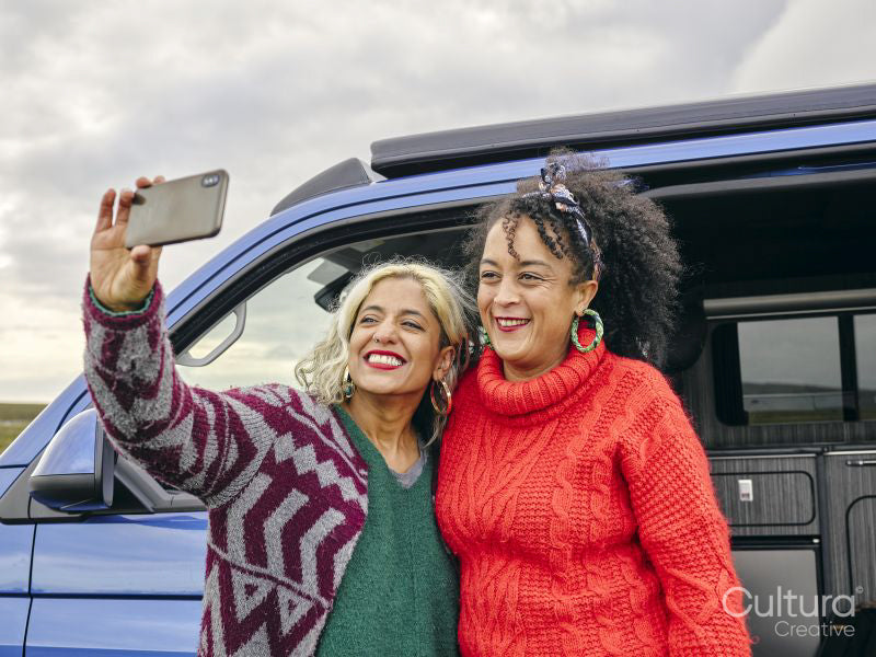 Female couple taking selfie in front of van