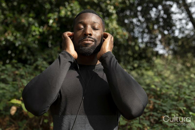 Portrait of athletic man with earbuds standing in park