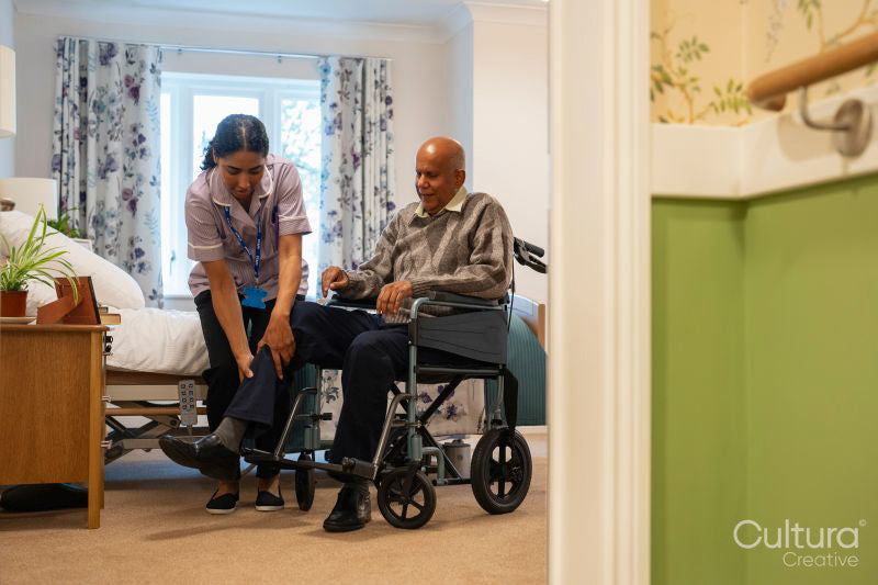 Nurse helping senior man to sit on wheelchair at nursing home