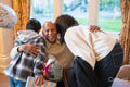 Mature woman and boy hugging senior man during birthday visit in nursing home