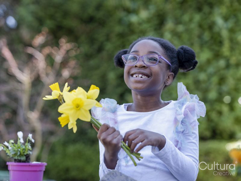 Smiling girl holding daffodils outdoors