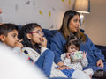 Mother with children sitting on sofa and watching TV