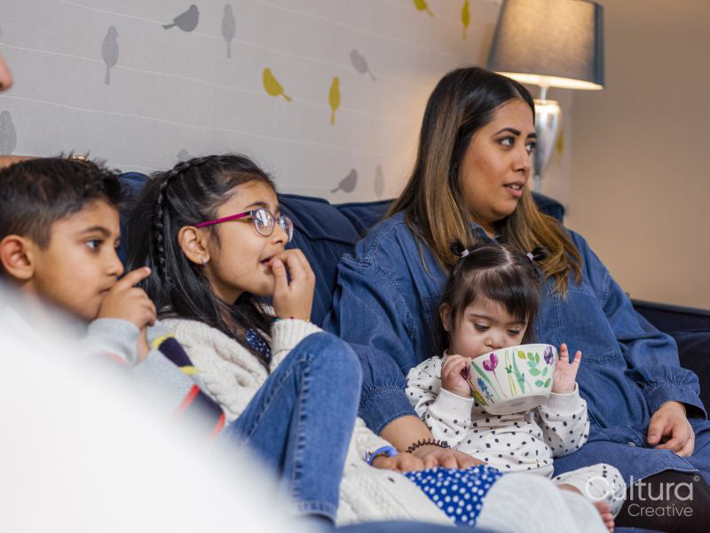 Mother with children sitting on sofa and watching TV
