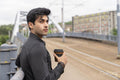 Young man leaning on railing with disposable cup