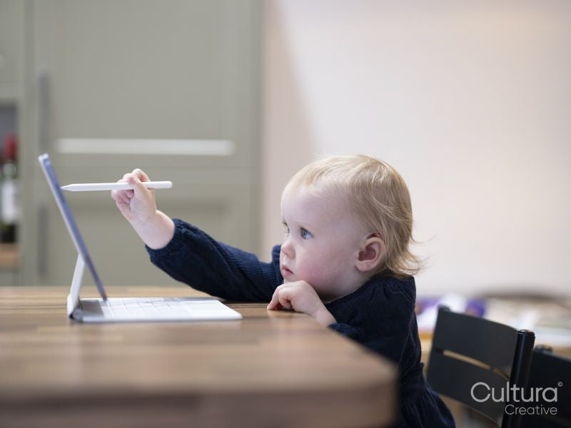 Blond girl wearing hearing aid drawing on digital tablet