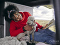 Woman sitting in back of van and playing with dog