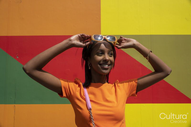 Smiling young woman standing against colorful wall