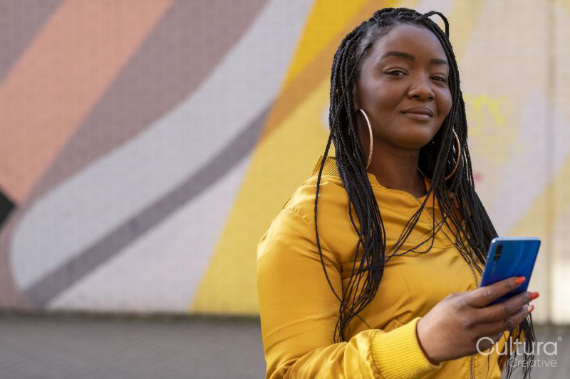 South Yorkshire, Portrait of woman with braided hair holding smart phone