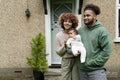 Parents holding baby daughter in front of home