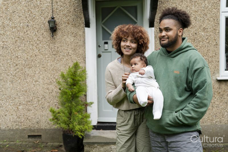 Parents holding baby daughter in front of home