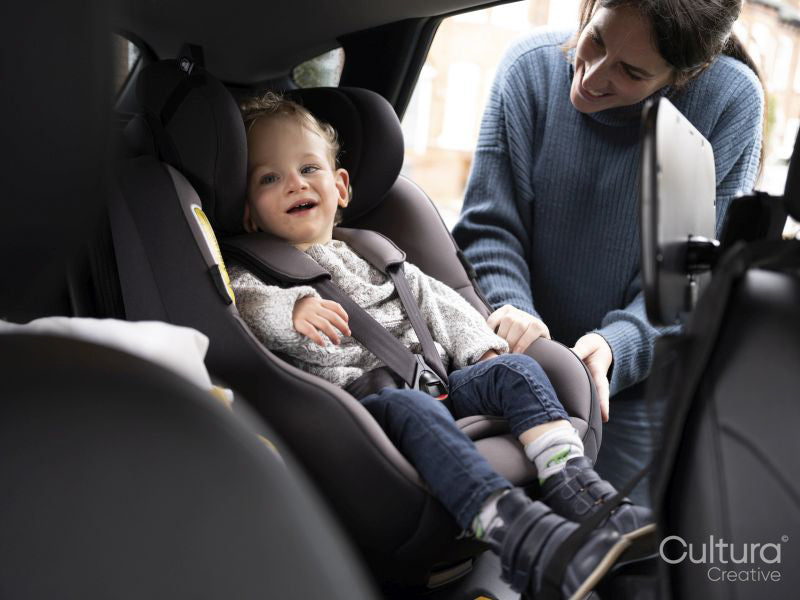 Mother looking at son seating in car seat