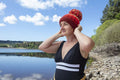 Woman in swimsuit and knit hat on lakeshore, Yorkshire, UK