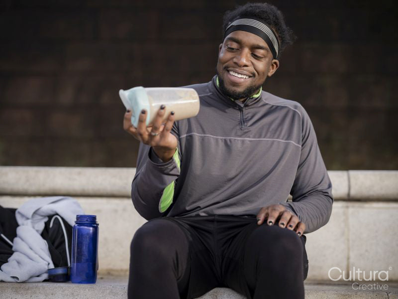 Athletic man preparing protein drink on steps outdoors