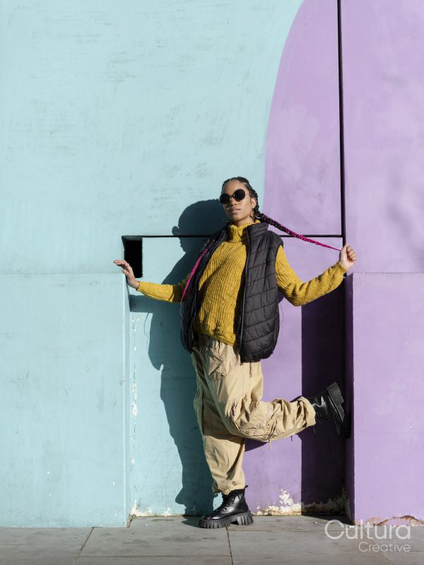 Portrait of young woman posing by colorful graffiti wall